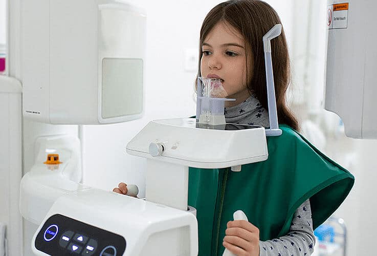 Young girl using a nebulizer inhaler in a bright medical or home healthcare setting.