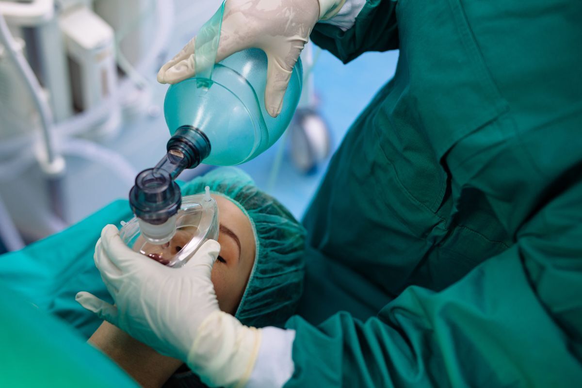 Dentist administering nitrous oxide sedation to anxious patient before dental procedure.